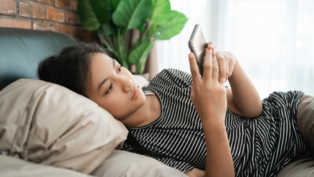 Thoughtful young African woman researching abortion pill services on her phone.