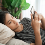 Thoughtful young African woman researching abortion pill services on her phone.
